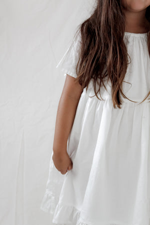 Girl wearing a White Dress With Bell Sleeves, Gathered Neckline, Ruffle Hem and Flowy Silhouette